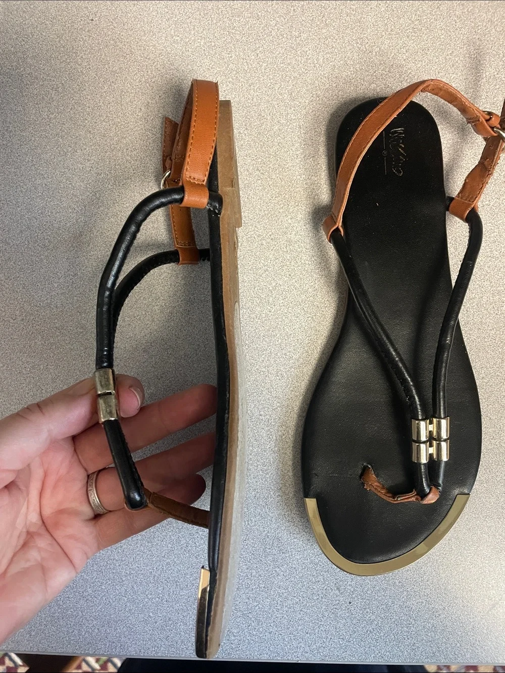 Black and brown t-strap sandals with gold accents